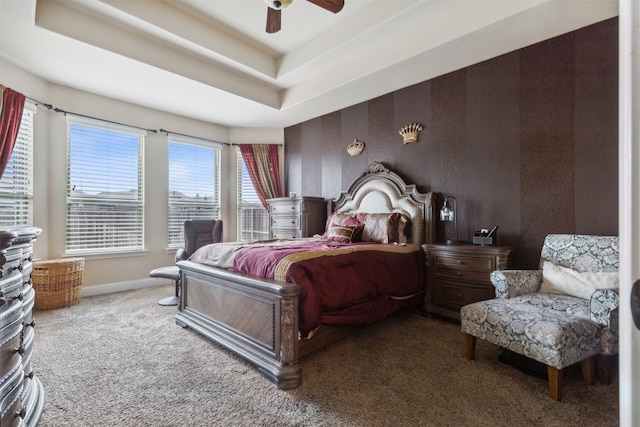 bedroom featuring ceiling fan, a tray ceiling, and carpet flooring