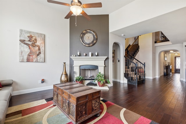 living room with dark hardwood / wood-style floors, ceiling fan, and a high ceiling