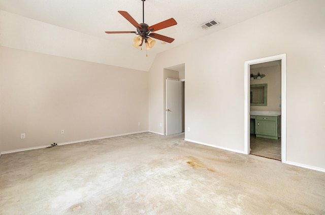 unfurnished bedroom featuring ceiling fan, vaulted ceiling, carpet floors, and ensuite bath