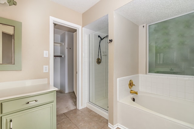 bathroom with tile floors, vanity, a textured ceiling, and plus walk in shower