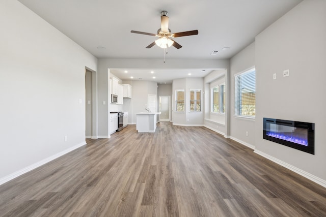 unfurnished living room with hardwood / wood-style floors and ceiling fan