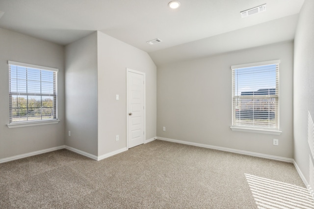 unfurnished bedroom featuring carpet flooring, a closet, lofted ceiling, and multiple windows