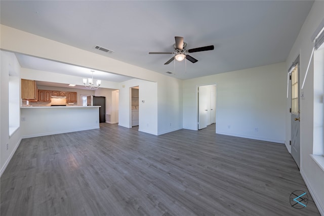 unfurnished living room featuring a healthy amount of sunlight, dark hardwood / wood-style floors, and ceiling fan with notable chandelier