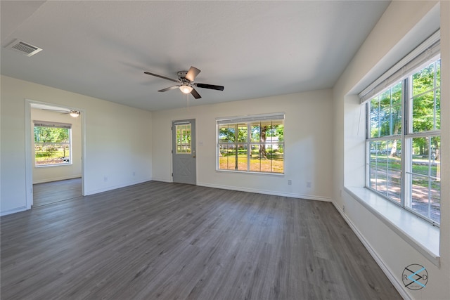 unfurnished room featuring dark hardwood / wood-style floors, ceiling fan, and a wealth of natural light