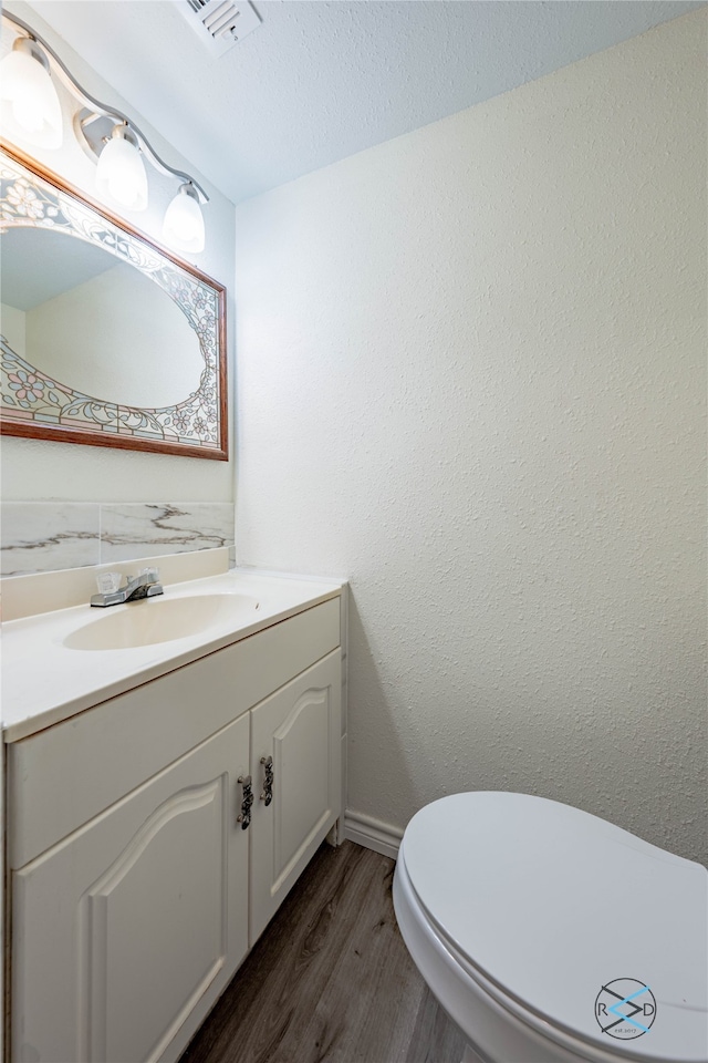 bathroom featuring hardwood / wood-style floors, toilet, vanity with extensive cabinet space, and a textured ceiling