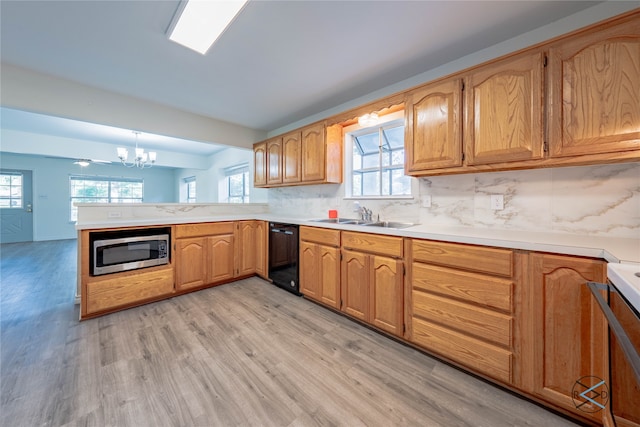 kitchen featuring a chandelier, dishwasher, stainless steel microwave, light wood-type flooring, and sink