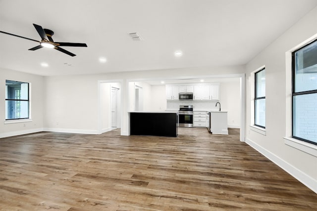 unfurnished living room featuring ceiling fan, hardwood / wood-style floors, and sink