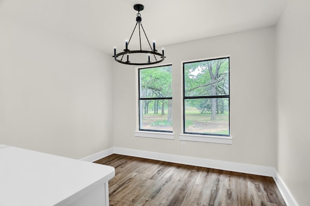 spare room with wood-type flooring and a chandelier