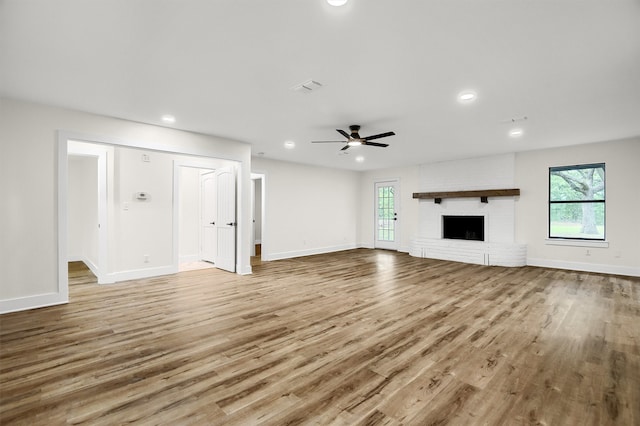 unfurnished living room with brick wall, ceiling fan, hardwood / wood-style flooring, and a fireplace