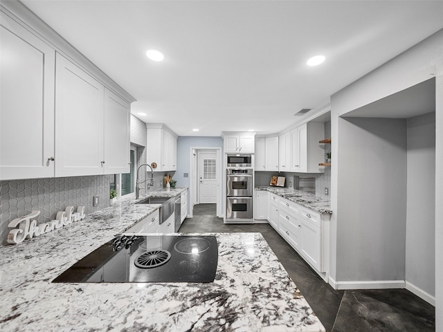 kitchen with white cabinets, light stone counters, sink, and appliances with stainless steel finishes