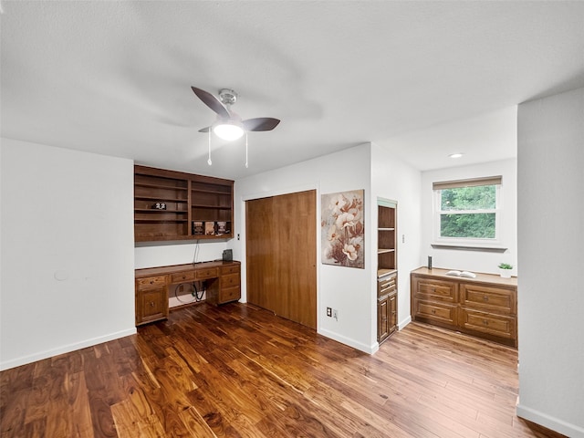 interior space with ceiling fan, dark hardwood / wood-style flooring, and built in desk