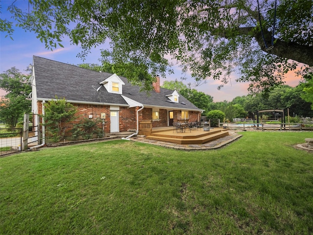 back house at dusk with a lawn and a wooden deck