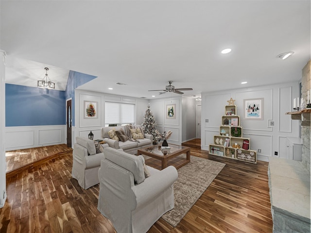 living room featuring dark hardwood / wood-style floors, a fireplace, and ceiling fan with notable chandelier