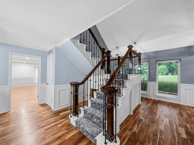 stairs featuring hardwood / wood-style floors, vaulted ceiling, and ornamental molding