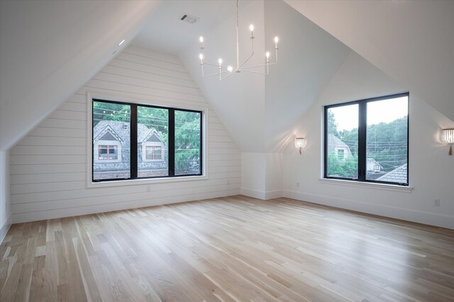 bonus room featuring light hardwood / wood-style flooring, a wealth of natural light, vaulted ceiling, and a chandelier