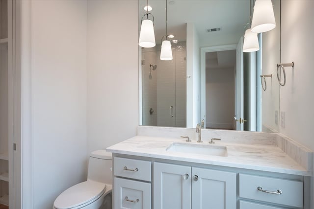 bathroom with a shower with shower door, vanity, and toilet