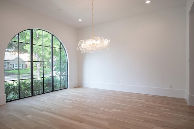 unfurnished room featuring light hardwood / wood-style floors and a notable chandelier