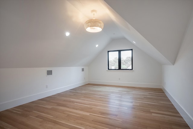 additional living space with light hardwood / wood-style flooring and lofted ceiling