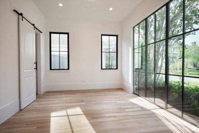 unfurnished bedroom featuring light hardwood / wood-style floors and a barn door