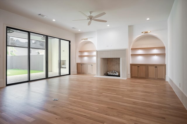 unfurnished living room featuring light wood-type flooring, ceiling fan, and built in shelves