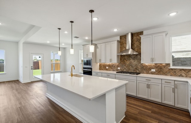 kitchen featuring wall chimney exhaust hood, dark hardwood / wood-style floors, pendant lighting, and a wealth of natural light