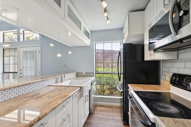 kitchen with decorative backsplash, stainless steel appliances, white cabinetry, and a wealth of natural light