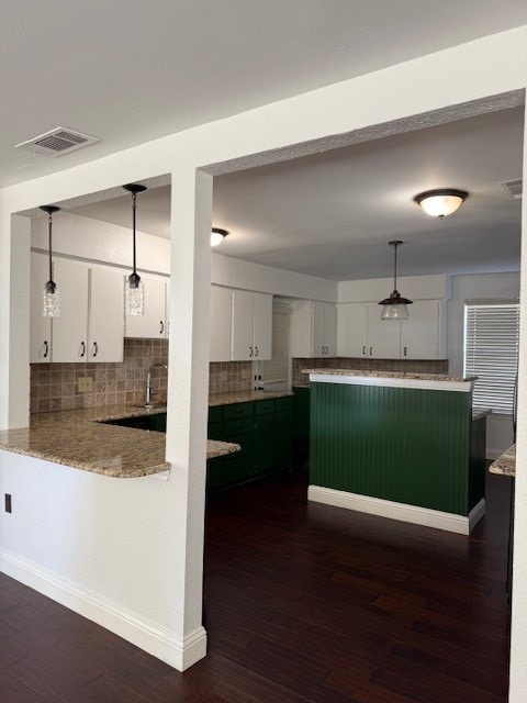 kitchen featuring kitchen peninsula, white cabinetry, dark hardwood / wood-style floors, and decorative light fixtures