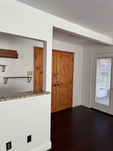 interior space with light stone counters and dark wood-type flooring