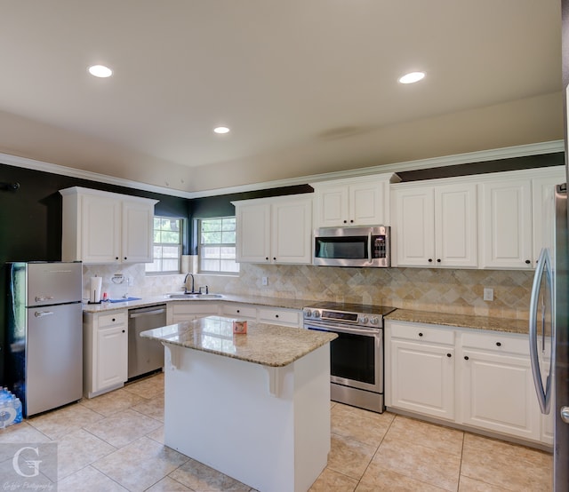 kitchen with a kitchen island, stainless steel appliances, backsplash, and white cabinetry