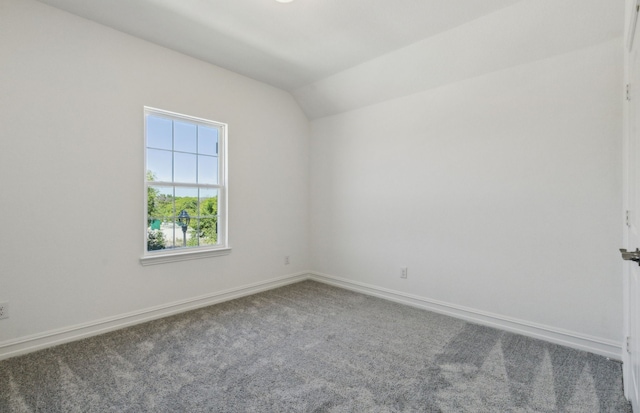 carpeted spare room with vaulted ceiling