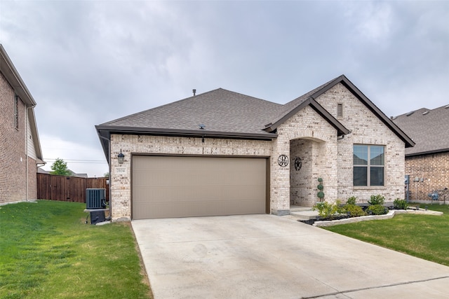 french country home with a front yard, a garage, and central AC unit