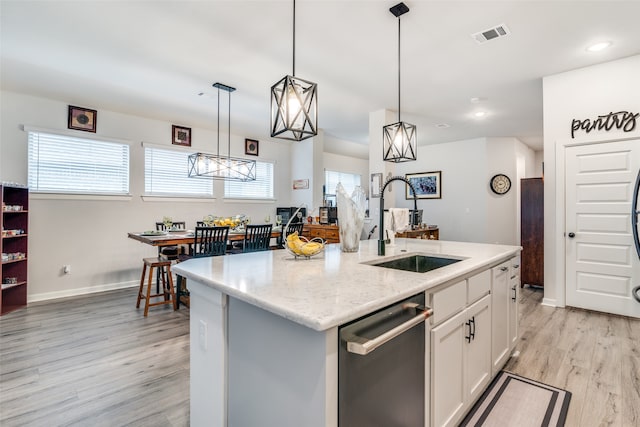 kitchen featuring light wood-type flooring, a kitchen island with sink, decorative light fixtures, sink, and dishwasher