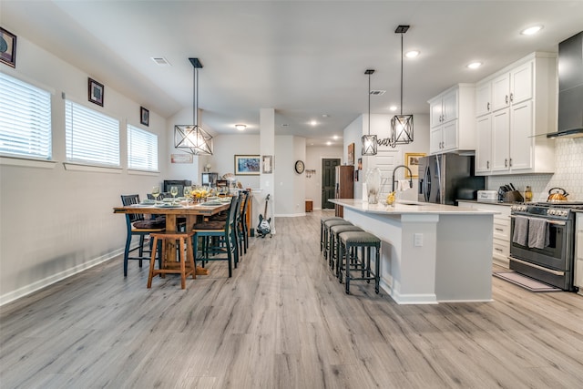 kitchen with stainless steel appliances, light hardwood / wood-style floors, and decorative light fixtures