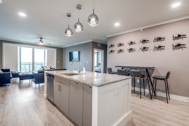 kitchen featuring ceiling fan, light hardwood / wood-style floors, sink, a kitchen island with sink, and ornamental molding