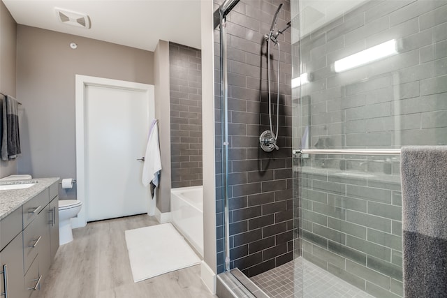 full bathroom featuring shower with separate bathtub, vanity, toilet, and hardwood / wood-style floors