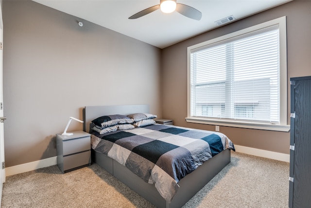 bedroom with ceiling fan, multiple windows, and light carpet