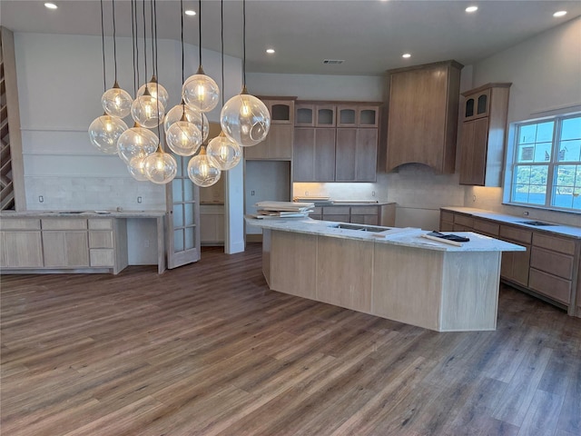 kitchen featuring dark hardwood / wood-style flooring, decorative backsplash, wall chimney exhaust hood, and a kitchen island with sink