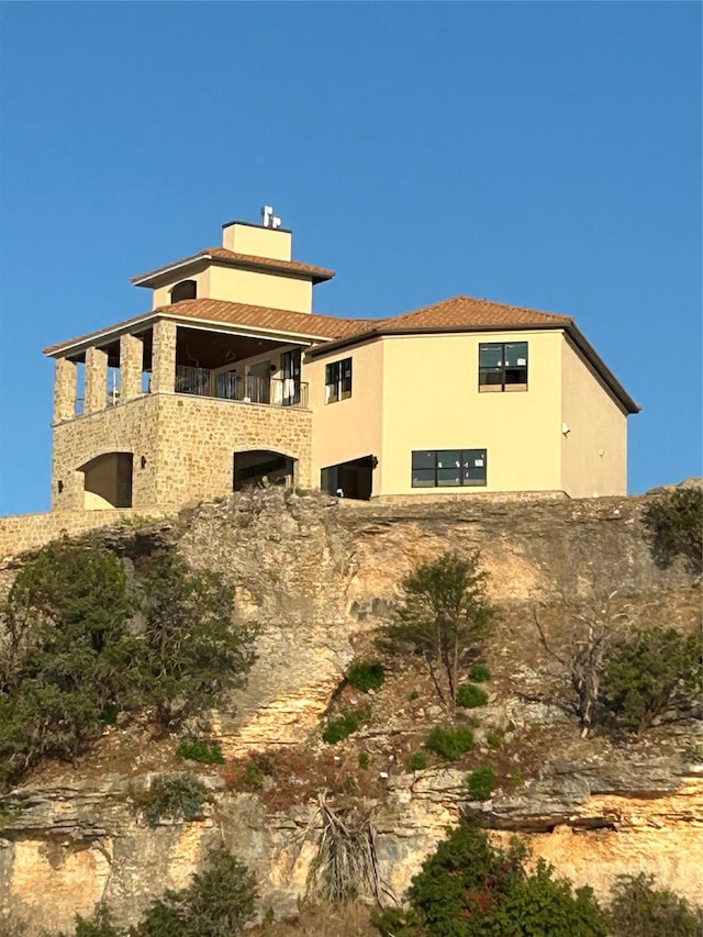 view of home's exterior featuring stucco siding, a balcony, and a chimney