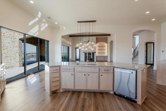 kitchen featuring a center island with sink, light brown cabinets, stainless steel dishwasher, and decorative light fixtures