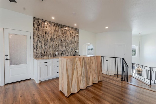 bar featuring white cabinets, hardwood / wood-style flooring, and backsplash