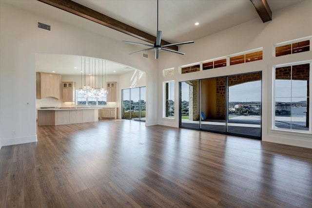 unfurnished living room featuring visible vents, beam ceiling, a healthy amount of sunlight, and dark wood-style floors