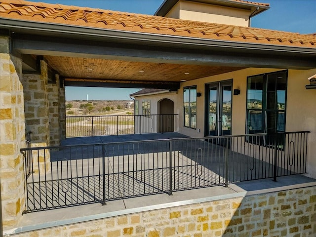 exterior space with a tiled roof, stone siding, and stucco siding