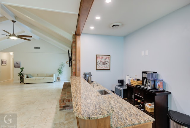 interior space with ceiling fan, beam ceiling, light stone counters, and light tile floors