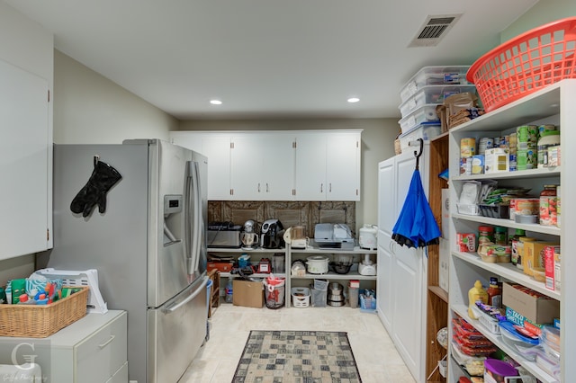 kitchen featuring stainless steel refrigerator with ice dispenser, light tile flooring, and white cabinetry