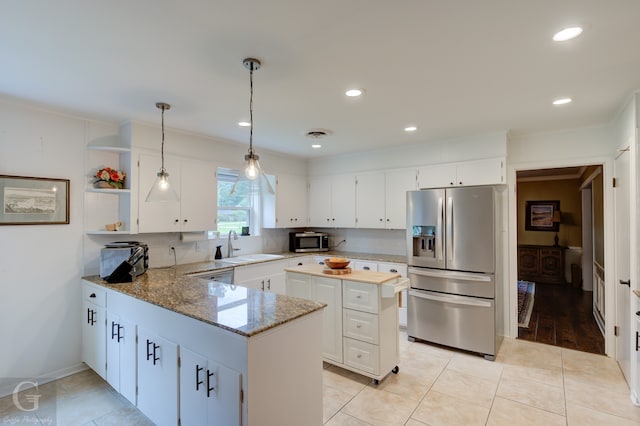 kitchen with hanging light fixtures, stainless steel appliances, kitchen peninsula, tasteful backsplash, and light tile flooring