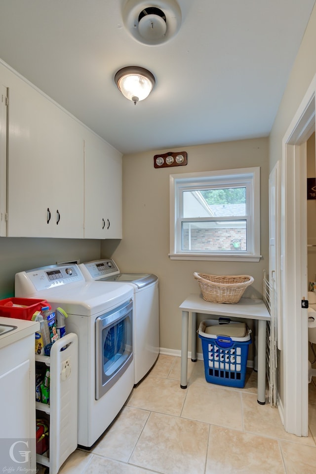 laundry room featuring washing machine and dryer, cabinets, and light tile floors