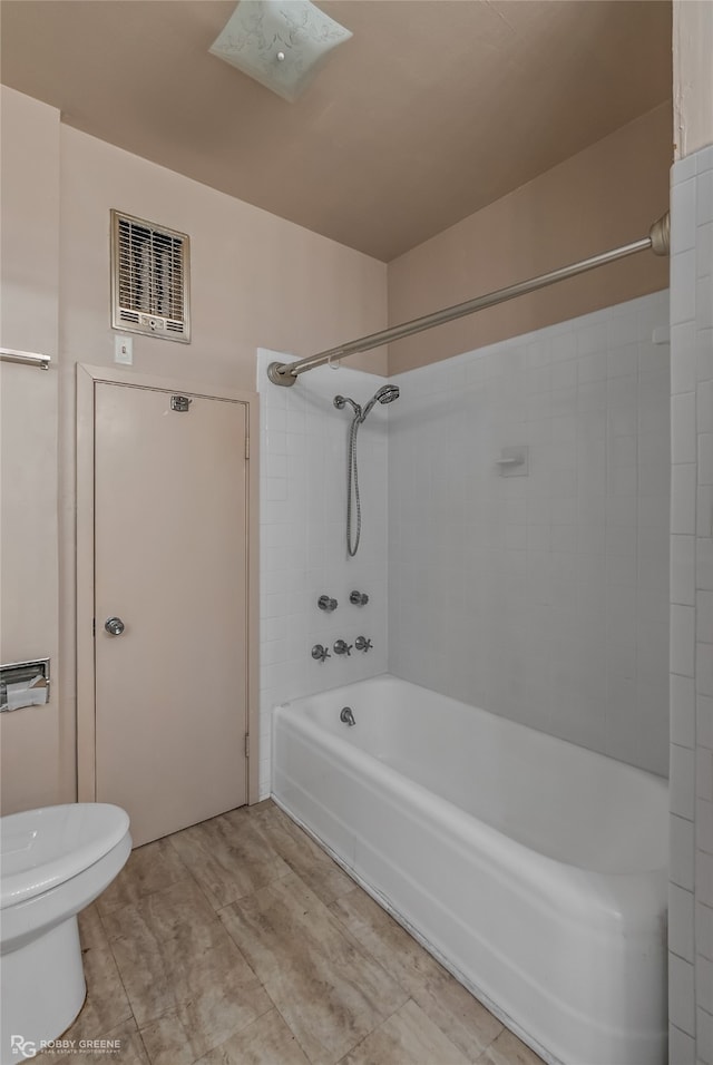 bathroom featuring tile floors, toilet, and tiled shower / bath combo