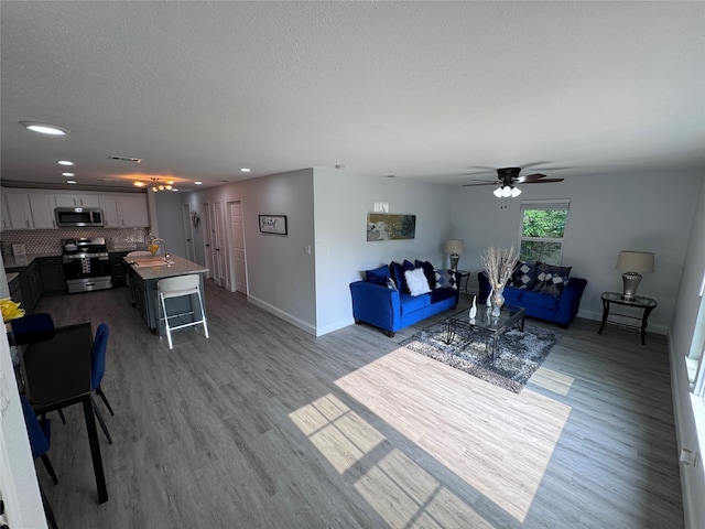 living room featuring ceiling fan, hardwood / wood-style flooring, and a textured ceiling