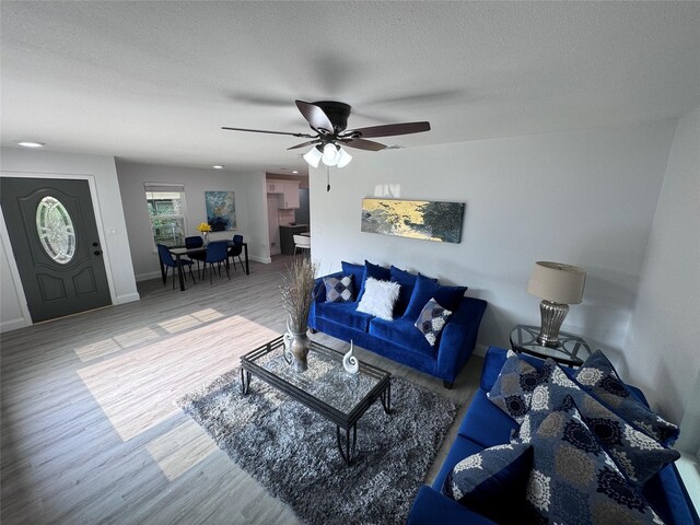 living room with ceiling fan, hardwood / wood-style floors, and a textured ceiling