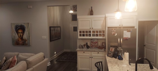 kitchen featuring stainless steel fridge, light stone counters, white cabinets, and pendant lighting